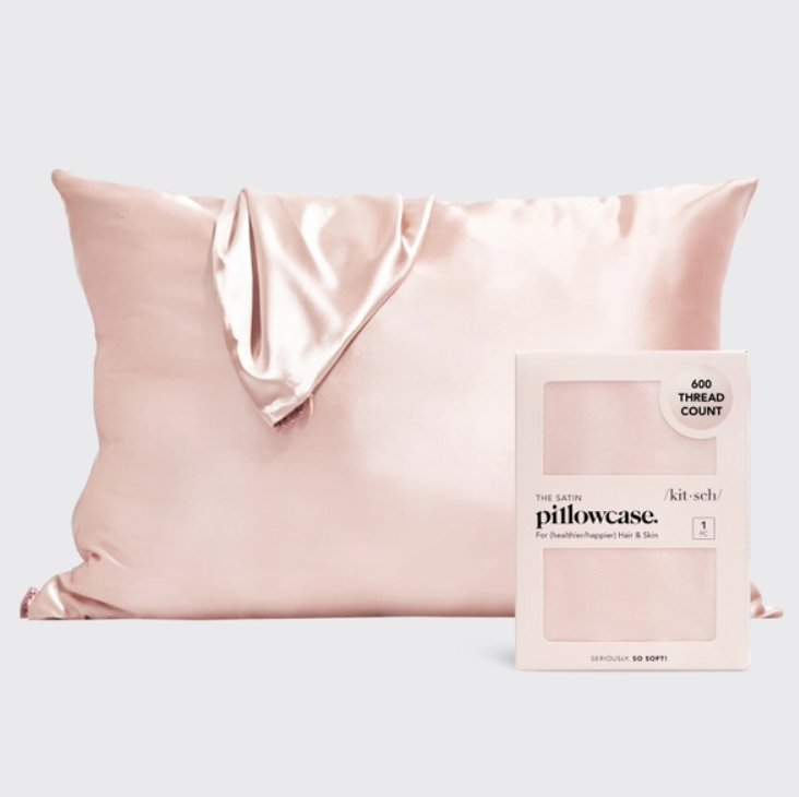 Product photo of a smooth blush pink satin pillowcase with elegant folds next to its Kitsch retail box featuring THE SATIN pillowcase 600 THREAD COUNT for hair and skin benefits