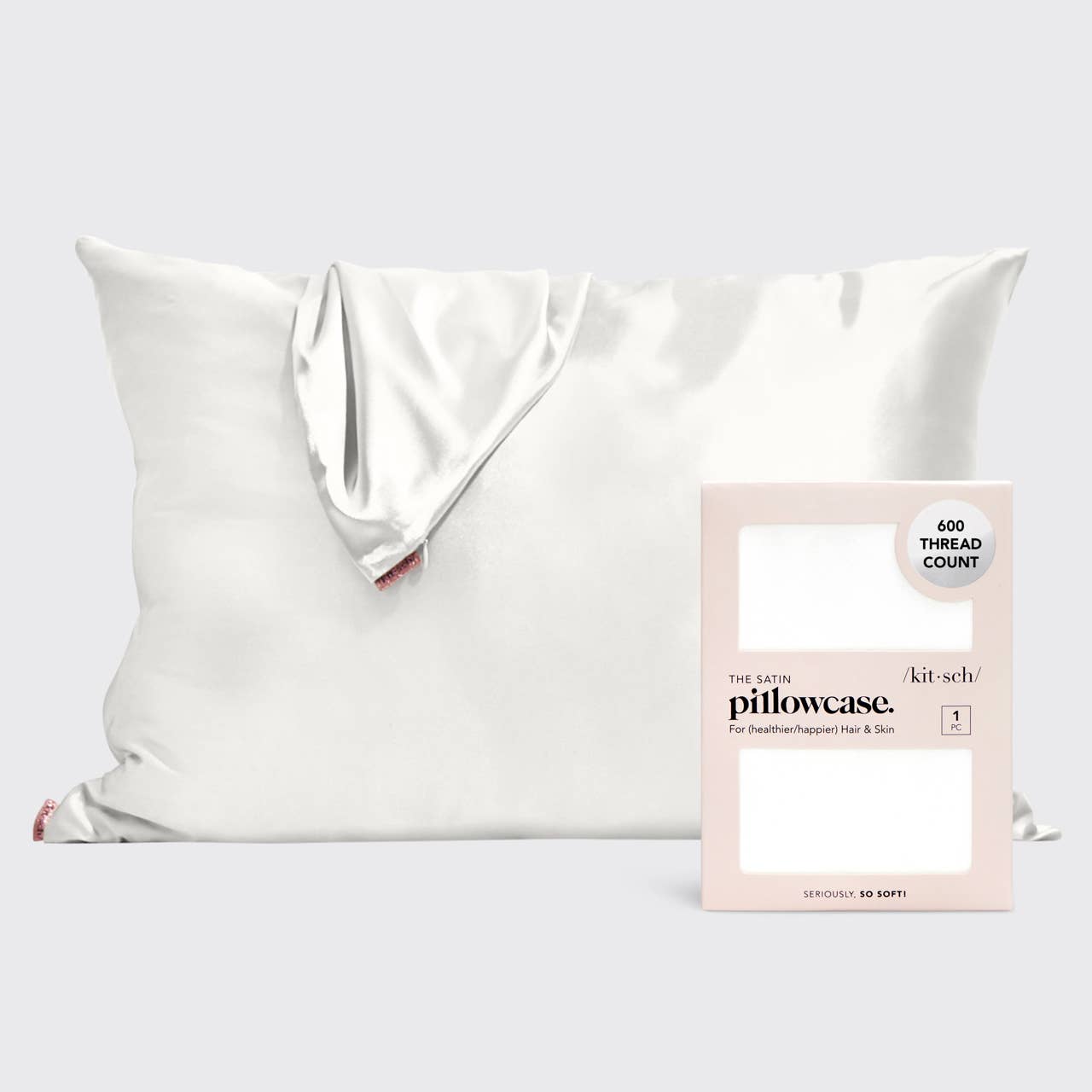 Kitsch white satin pillowcase draped showing a small red tag next to its pink packaging highlighting 600 thread count and the text Seriously So Soft