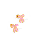 A pair of gold-toned stud earrings in a bow shape with vibrant pink enamel detailing forming a grid pattern, presented on a white background