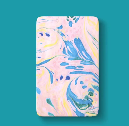 A rounded rectangular object displaying a marbled pattern of flowing pastel pink, light yellow, and bright blue swirls with teal accents, featuring a small 'OST' logo