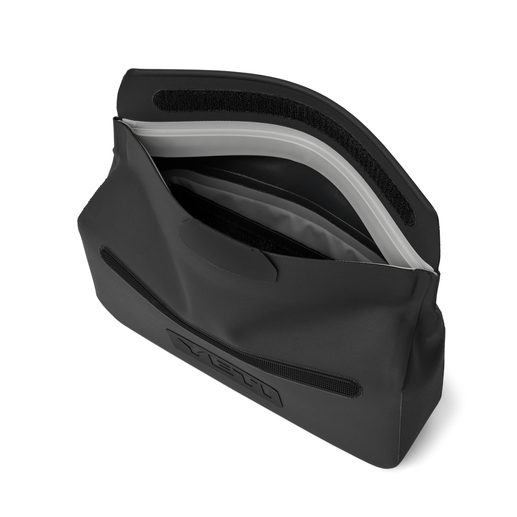 Product photography of a partially open matte black YETI SideKick Dry Gear Case showcasing its light gray waterproof zipper seal, Velcro flap, and embossed YETI logo