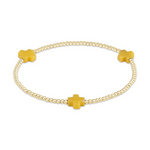 A delicate stretch bracelet featuring small gold beads interspersed with three vibrant mustard yellow cross-shaped charms