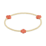 Jewelry: A delicate gold beaded stretch bracelet featuring three vibrant coral-colored cross-shaped accents