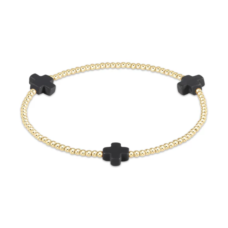 Gold beaded stretch bracelet featuring three matte black quatrefoil cross charms on a white background