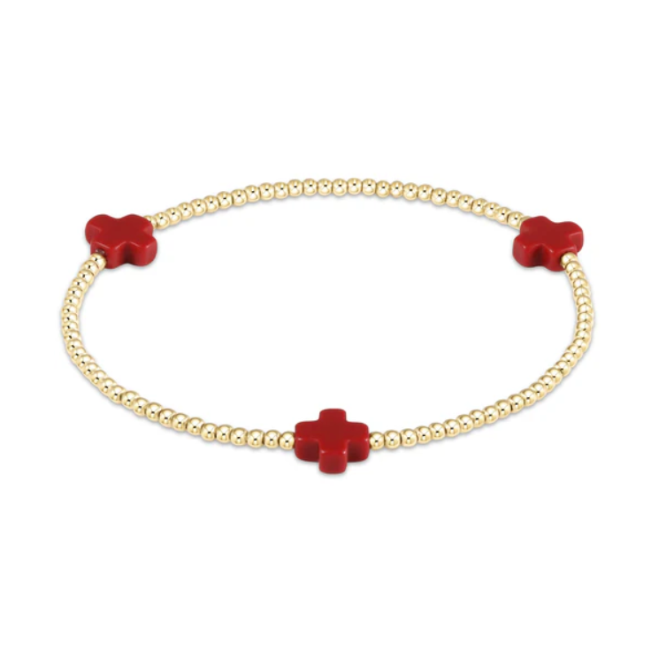 A gold beaded stretch bracelet featuring three vibrant red enamel cross charms evenly spaced on a white background