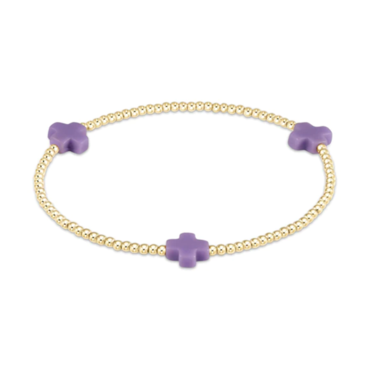 Jewelry gold beaded stretch bracelet with three matte lilac purple cross charms on a white background