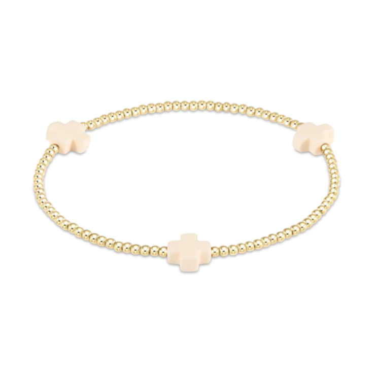 Gold-toned beaded stretch bracelet with three pale pink cross-shaped charms