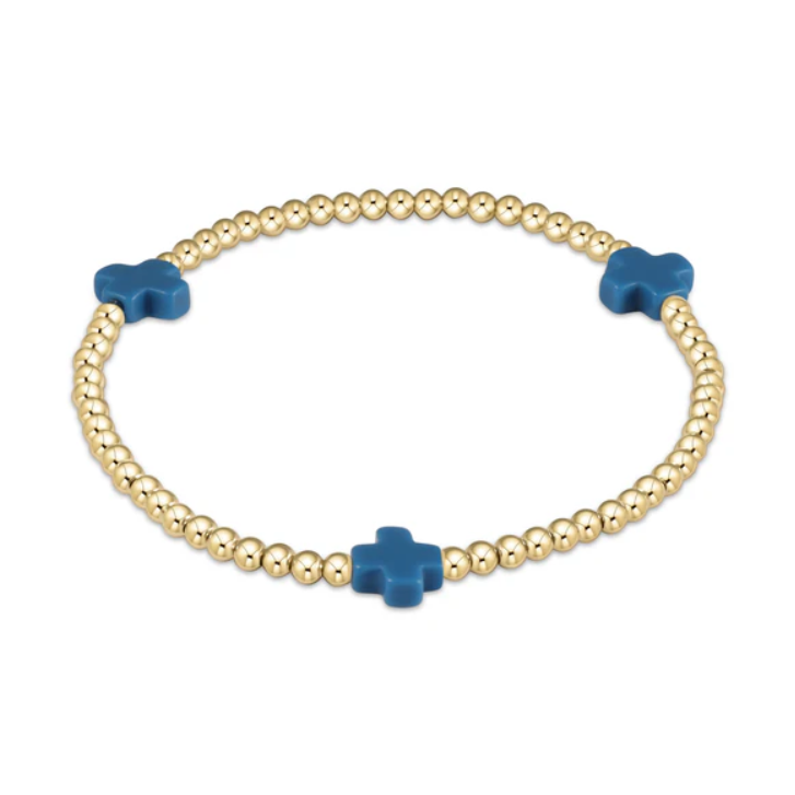 A stretch bracelet crafted from small gold beads featuring three vibrant blue cross-shaped charms