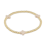 A gold beaded stretch bracelet on a white background featuring three evenly spaced light pink cross charms