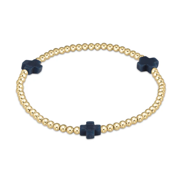 Jewelry: A sleek gold beaded bracelet featuring three dark blue matte cross charms