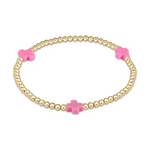 A gold beaded stretch bracelet features three vibrant pink cross-shaped charms on a pristine white background