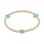 A gold-tone beaded elastic bracelet featuring three spaced mint green cross-shaped beads on a white background