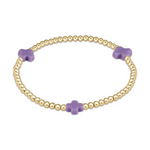 Jewelry: a gold beaded stretch bracelet adorned with three small lilac cross-shaped beads