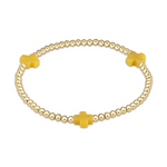 Gold beaded stretch bracelet with three matte mustard yellow cross charms on a white background