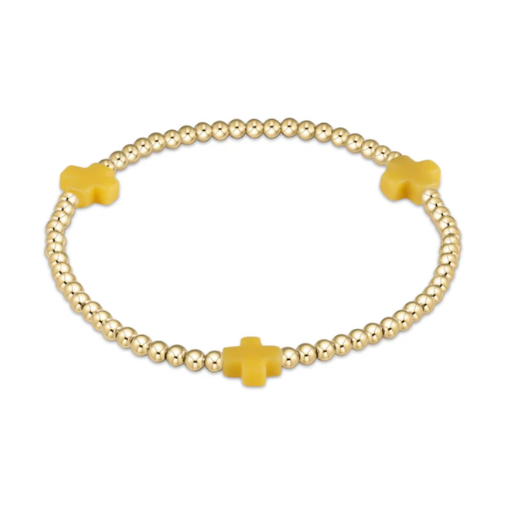 Gold beaded stretch bracelet with three matte mustard yellow cross charms on a white background