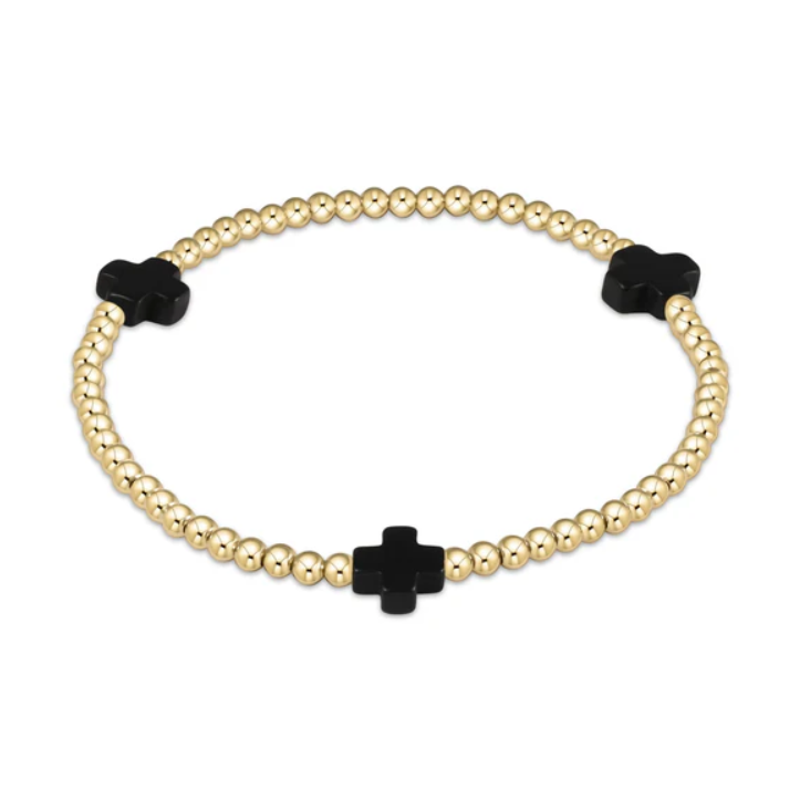 A gold beaded stretch bracelet featuring three polished black cross-shaped charms
