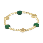 Gold beaded bracelet featuring three faceted dark green oval gemstones and three gold four-leaf clover charms on a white background