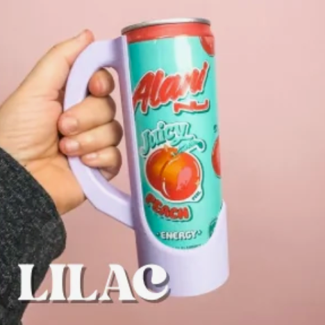 A hand holds a vibrant teal green Alani Nu Juicy Peach Energy drink can featuring bold red peach graphics within a lilac purple handled can holder set against a soft pink background with the word LILAC visible