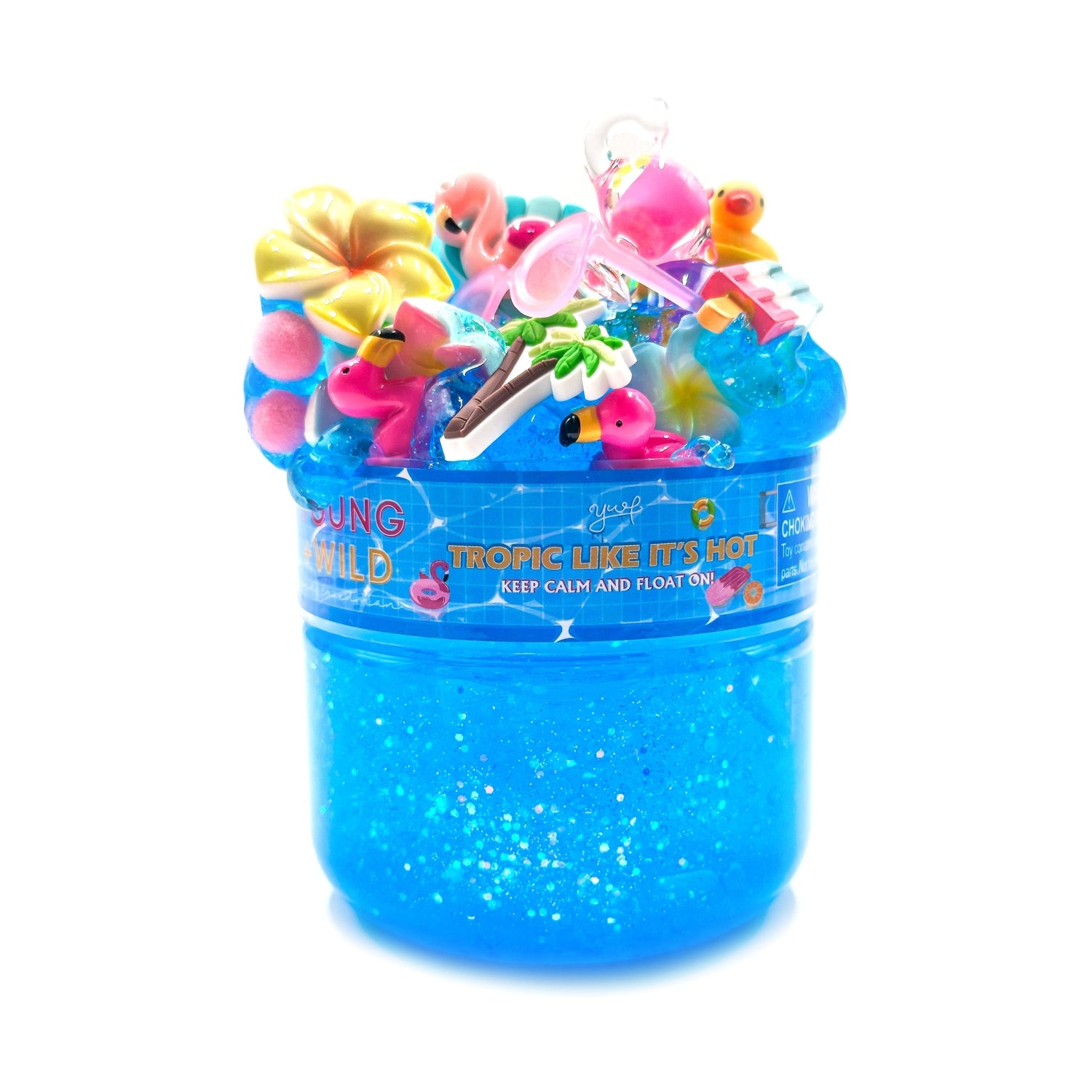 Yoof Slime's glitter blue slime in a plastic container topped with tropical charms including pink flamingos a yellow plumeria flower a mini palm tree and a 'Tropic Like It's Hot' label