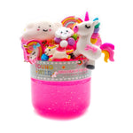 A product image of a 'Young + Wild Unicorn in the Clouds' kit featuring a white unicorn with a rainbow mane and tail, smiling clouds, and a vibrant rainbow above a clear pot of sparkling pink glitter