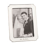 Silver-plated photo frame by Mud Pie displaying a black and white wedding portrait of a smiling bride and groom against a subtle stone building, highlighted by the frame's elegant wavy edge and engraved mr & mrs text
