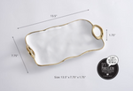Pampa Bay porcelain serving tray in white with an organic wavy shape, gold trim, and two open-loop gold handles, displaying dimensions of 13.5 by 7.75 by 1.75 inches
