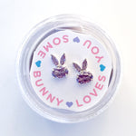 Pair of purple crystal bunny shaped stud earrings in a circular plastic container