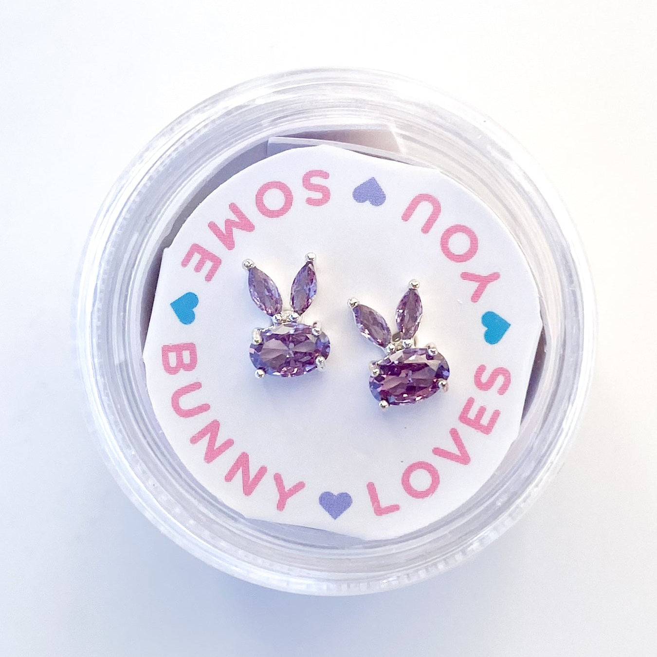 Pair of purple crystal bunny shaped stud earrings in a circular plastic container
