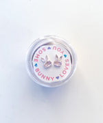 Pair of silver bunny shaped stud earrings with pink stones in a circular clear container