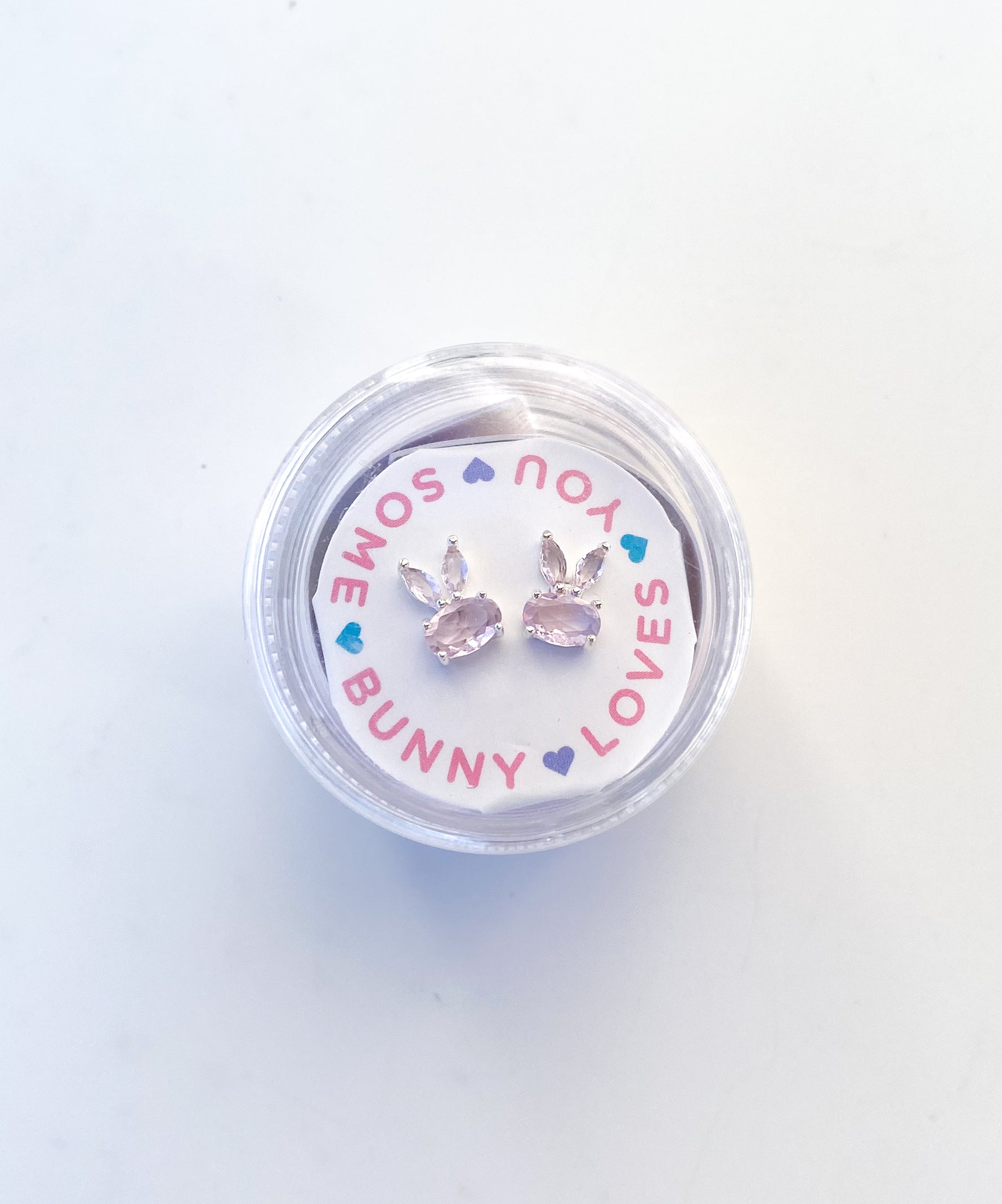 Pair of silver bunny shaped stud earrings with pink stones in a circular clear container