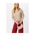 Woman wearing a beige crew neck sweater and red trousers holding a small beige studded handbag