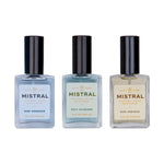 Three Mistral Eau de Parfum for Men bottles, featuring clear glass and black caps, displaying light blue Surf Hossegor, light teal Golf Valbonne, and light yellow Ride Ventoux fragrances