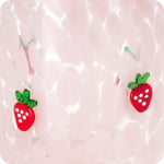 Pink speckled glass surface with two small red strawberry glass appliques