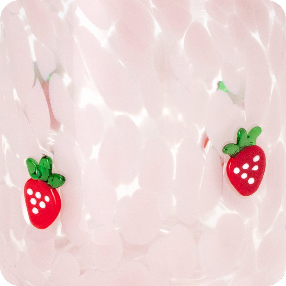 Pink speckled glass surface with two small red strawberry glass appliques