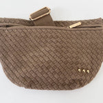 Product photography by Pretty Simple of a brown woven crossbody bag on a white background featuring an intricate lattice texture, three small gold-tone studs, and a wide adjustable canvas strap with metallic hardware