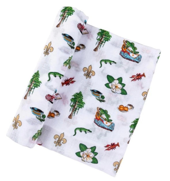 White muslin baby swaddle with Louisiana themed icons including alligators, crawfish, magnolias, and fleur de lis