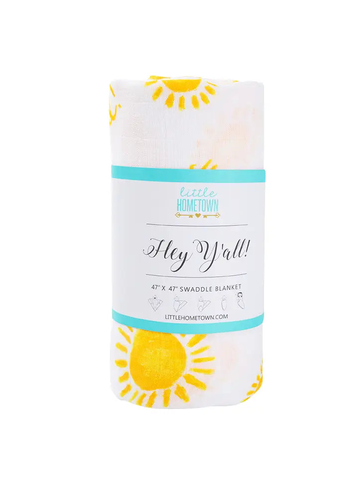 Rolled white swaddle blanket with yellow sun pattern and Little Hometown brand packaging