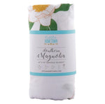 Folded white swaddle blanket with magnolia flower print and Little Hometown product label