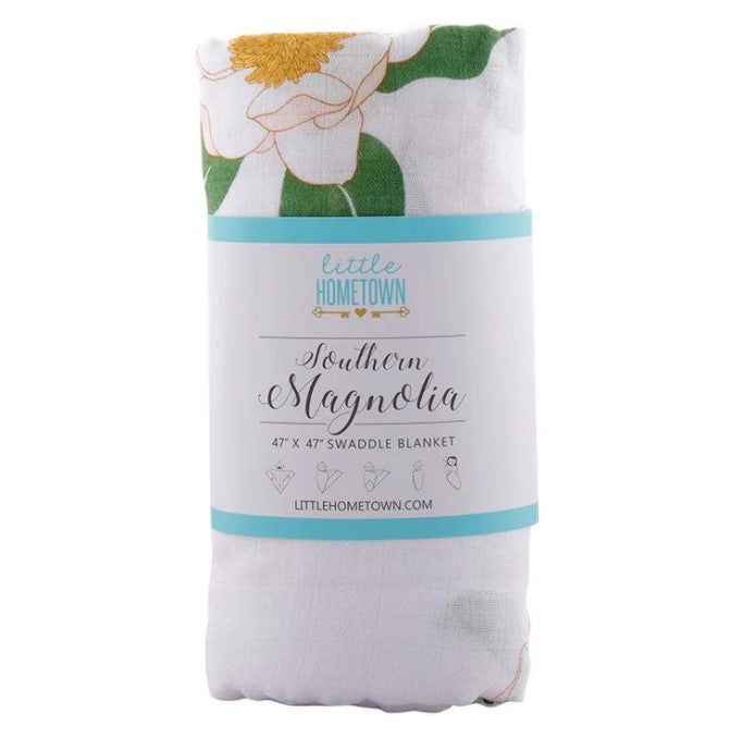 Folded white swaddle blanket with magnolia flower print and Little Hometown product label