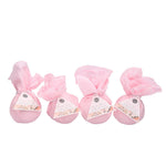 Four Sweet Grace bath bombs wrapped in pink tissue paper with triangular product labels