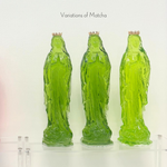Three green glass statues of the Virgin Mary with crowns on a clear shelf