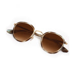 A pair of round sunglasses with brown gradient lenses light tortoise shell frames and gold metal accents on a white studio background