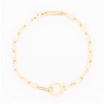 Michelle McDowell gold jewelry, a paperclip chain bracelet arranged in a circle on a white background, featuring elongated rectangular links and a round toggle clasp with an engraved brand tag