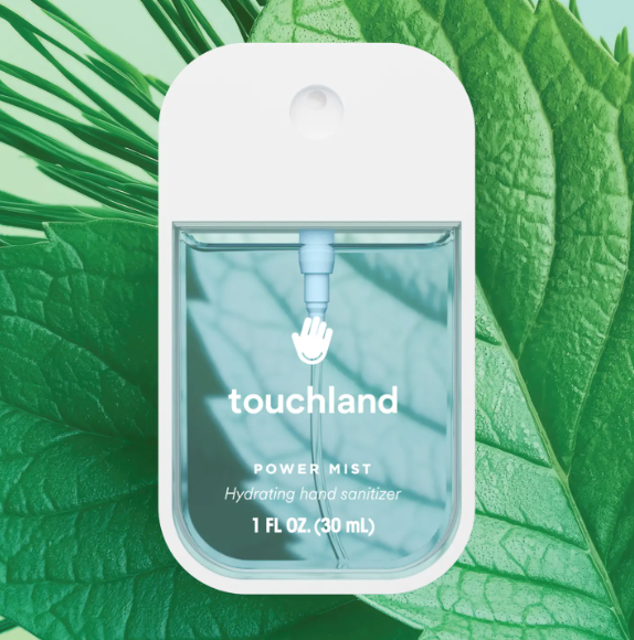 Touchland Power Mist hydrating hand sanitizer spray bottle against green leaves