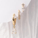 A set of three gold and crystal earrings featuring a large hoop with a dangling teardrop-shaped crystal a smaller pave-set hoop and a stud with a marquise and round crystal