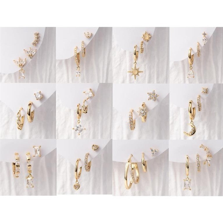 Gold earrings collection showcasing a variety of gold-toned hoop, stud, and dangle earrings with sparkling clear gemstones, featuring star, crescent moon, and heart designs displayed on white backgrounds