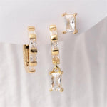 A trio of gold-toned earrings featuring clear baguette-cut stones, including a pavé hoop, a dangling hoop, and a single stud earring