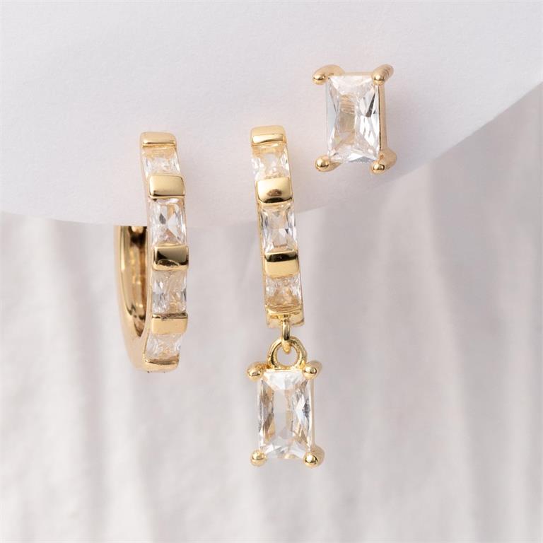 A trio of gold-toned earrings featuring clear baguette-cut stones, including a pavé hoop, a dangling hoop, and a single stud earring