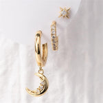 Gold jewelry set with celestial-themed earrings including a dangling crescent moon hoop with clear gems, a pavé huggie hoop, and a starburst stud