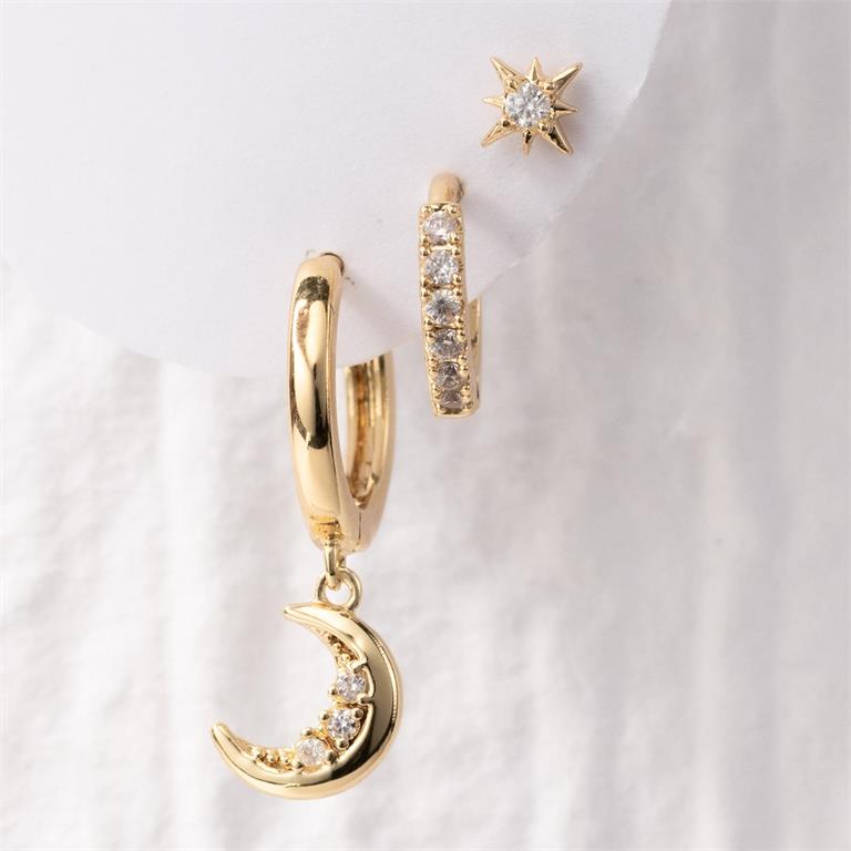 Gold jewelry set with celestial-themed earrings including a dangling crescent moon hoop with clear gems, a pavé huggie hoop, and a starburst stud